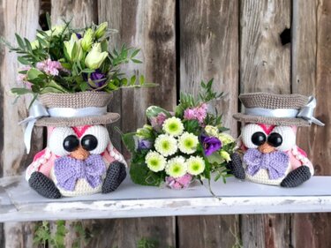 Pair of crocheted owl flower holders with ribbon hats arranged as a table centerpiece
