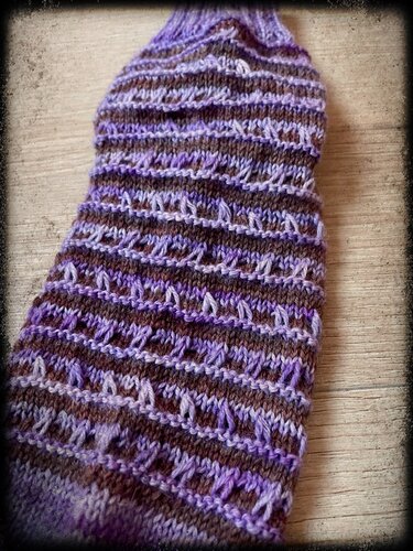 Gestrickte Socke oder Beinstulpe in Lila und Braun mit Lochstreifen