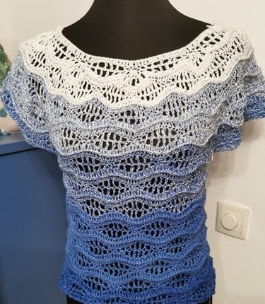 Kurzärmeliges Häkelshirt in Weiß und Blau auf Schaufensterpuppe, deutlich sichtbares Wellen‑Lochmuster