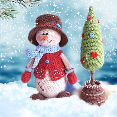 Gehäkelter Schneemann-Amigurumi mit braunem Hut und grüner Tanne im Schnee