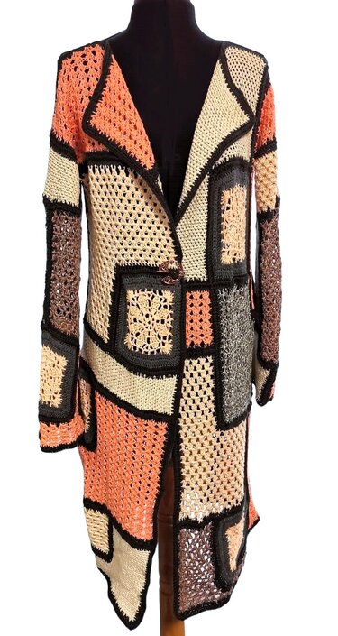 Boho-Häkelmantel aus verschiedenfarbigen Quadraten in Creme, Apricot und Braun mit schwarzer Kontur auf Puppe