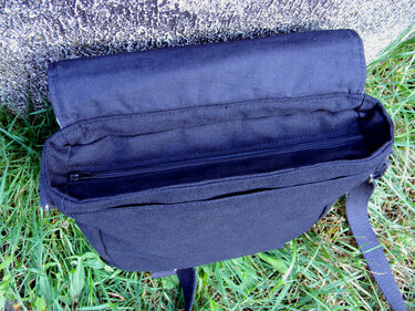 Nahaufnahme einer geöffneten schwarzen Umhängetasche mit innenliegendem Reißverschluss und offenem Hauptfach