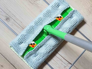 Detailaufnahme gestrickter hellgrauer Moppbezug mit Kästchenmuster auf grünem Moppkopf