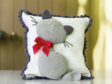 Grey 3D cat appliqué on white crocheted pillow cover with pink bow