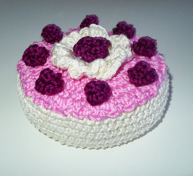 runde gehäkelte Spielzeugtorte weiß-rosa mit violetten Röschen