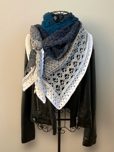 Ombre crocheted triangle shawl in teal, gray, and white with openwork lace edges, draped over a black jacket.