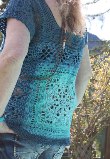 Rückenansicht eines türkis-blauen gehäkelten Damen-Tops mit Blumen-Motivquadraten und Farbverlauf