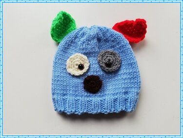 Blaue gestrickte Babymütze mit Tiergesicht und bunten Ohren