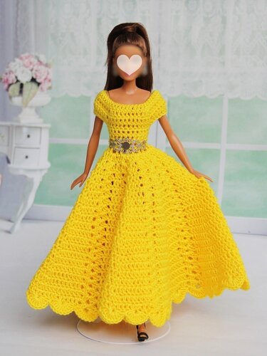 Fashion doll wearing a hand-crocheted yellow dress with a fitted bodice, full scalloped skirt and decorative belt.