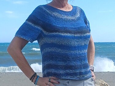 Person am Strand trägt maritimes blau-graues kurzärmliges Strickshirt