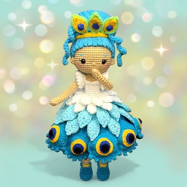 Blue peacock-inspired amigurumi crochet doll wearing a crown and layered petal skirt