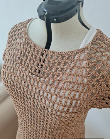 Beigefarbenes gehäkeltes Damen‑Shirt mit Ajourmuster auf Schneiderpuppe