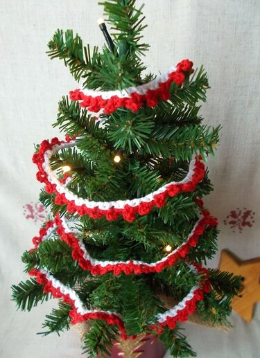 Mini-Tannenbaum mit rot-weißer, gezackter Häkelgirlande und dezenten Lichtern