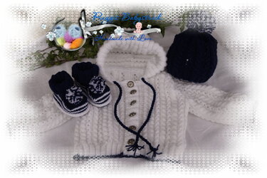 Gestricktes Babyset mit weißer Kapuzenjacke, dunkelblauer Mütze und dunkelblauen Schühchen.