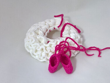 Gehäkelter weißer Rüschenkragen mit zwei pinken Mini-Ballerinas auf hellem Hintergrund
