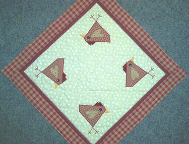 Quadratische Decke diagonal gelegt mit kariertem Rand und vier applizierten Vögeln