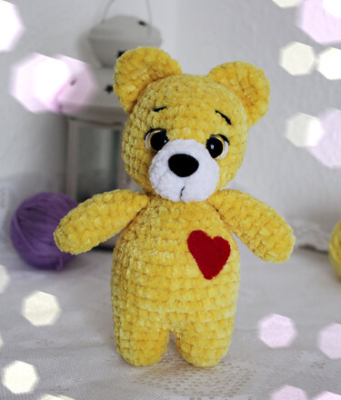 Front view of yellow amigurumi teddy bear with red heart appliqué