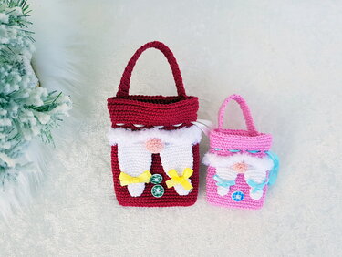 Zwei gehäkelte Wichtel-Taschen, eine rot und eine rosa, mit Griffen, weißen Bärten und Schleifen