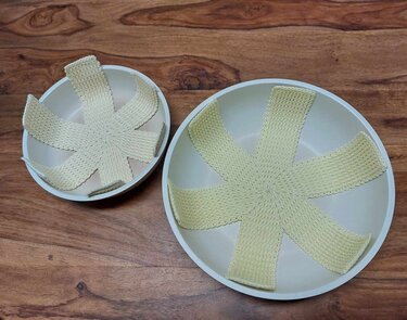 Zwei Schalen mit sternförmigen, gehäkelten Einlagen auf einem Holztisch