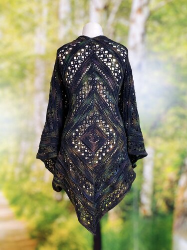 Back view of a dark variegated crocheted shawl on a mannequin, showing diamond and chevron openwork motifs and an asymmetrical hem.