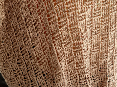 Beige crochet material displaying a consistent diagonal open-stitch pattern.
