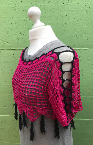 Gehäkelter Bolero in Pink und Schwarz mit Lochmuster und Fransen auf einer Schneiderpuppe