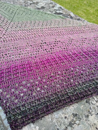 Gehäkeltes Dreieckstuch in Grün, Pink und Lila mit Lochmuster auf Stein