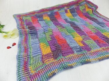 Gehäkelte Decke mit Reliefstäbchen und farbenfrohem Rand