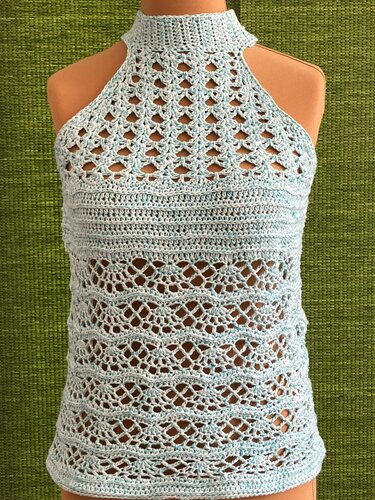 Hellblaues gehäkeltes Damen-Top mit hohem Stehkragen und Lochmuster auf Schaufensterpuppe vor grünem Hintergrund