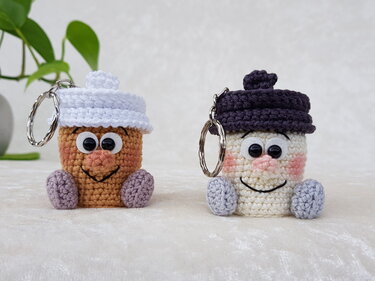 Zwei schnell gehäkelte Amigurumi-Schlüsselanhänger, ein brauner mit weißer Mütze und ein cremefarbener mit dunkler Mütze