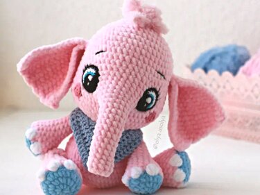 pink crocheted amigurumi elephant with long trunk, floppy ears and blue paw pads