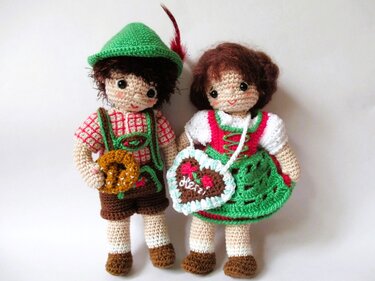 Zwei gehäkelte Amigurumi-Puppen in Tracht: Junge mit Lederhose und Brezel, Mädchen im Dirndl mit Lebkuchenherz