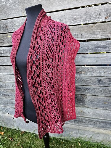 Bordeauxroter gehäkelter Spitzenschal mit Lochmuster auf schwarzer Büste vor Holzlatten