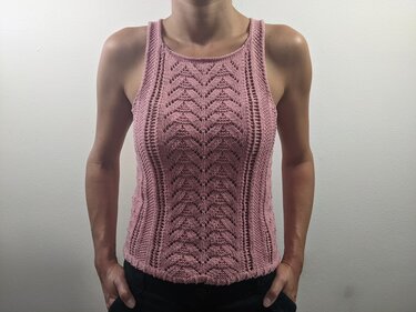 Vorderansicht eines ärmellosen Stricktops in Rosa mit Zopf- und Ajourmustern auf einer Person