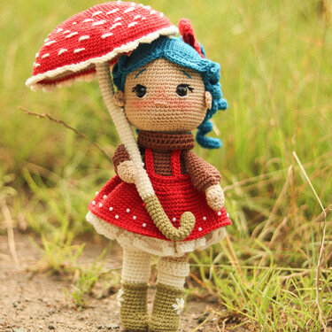 Gehäkelte Amigurumi-Puppe mit blauem Haar, rotem Kleid und Pilzschirm