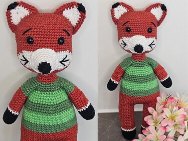 Amigurumi-Fuchs gehäkelt, zwei Ansichten: rötlicher Fuchs mit grün gestreiftem Pullover, weißer Schnauze und schwarzen Pfoten.