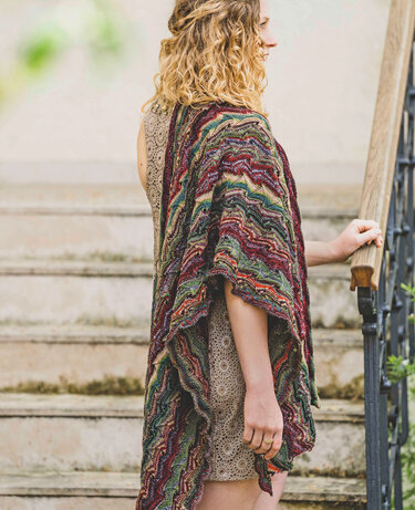 Seitlich stehende Person auf Treppe trägt mehrfarbiges gestricktes Lacetuch mit wellenförmigem Streifenmuster