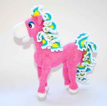 Rosa gehäkeltes Einhorn mit mehrfarbiger Mähne und hellen Hufen