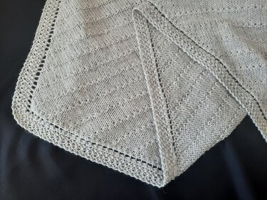 Hellgraues gestricktes Dreieckstuch mit feinem Strukturmuster und Lochrand