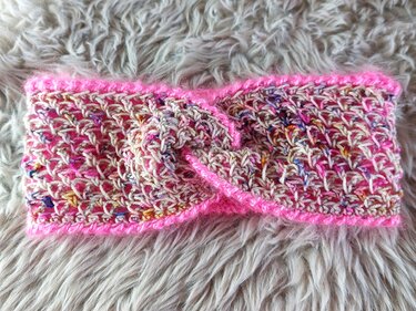 Kompaktes gehäkeltes Stirnband mit mittiger Drehung und pinker Umrandung
