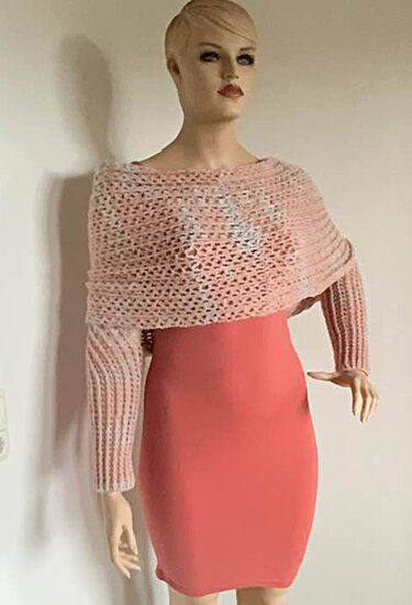 Gehäkelter zartrosa Bolero mit langen Ärmeln und Lochmuster über korallfarbenem Kleid auf Schaufensterpuppe.