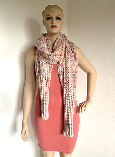 Gehäkelter rosé-weißer Schal an einer Schaufensterpuppe über einem korallfarbenen Kleid