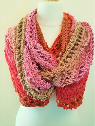 Gehäkelter Loop-Schal in Rosa, Beige und Rot-Orange mit offenem Muster auf einer Schaufensterpuppe.