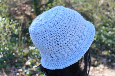 Hellblaue gehäkelte Damenmütze mit kurzem Rand, Rückansicht im Freien