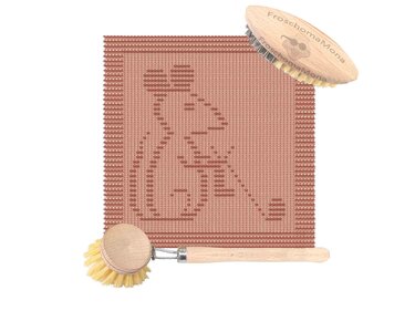 Gestricktes, terrakottafarbenes Tuch mit Froschmotiv und zwei Holzspülbürsten auf weißem Hintergrund.