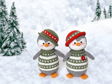 Two crocheted penguin amigurumi wearing green striped sweaters and tilted hats on a snowy background
