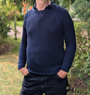 Mann trägt dunkelblauen gehäkelten Pullover mit strukturiertem Muster und Rundhalsausschnitt