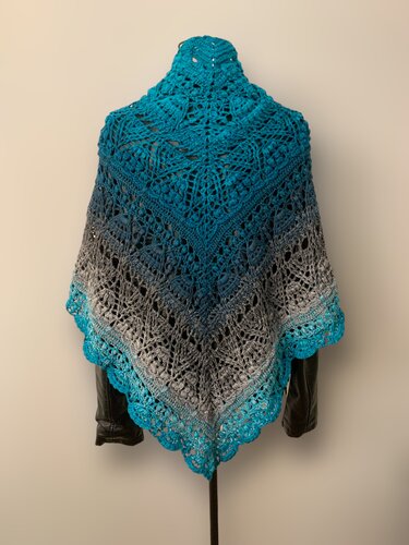 Teal and grey ombre crochet triangle shawl with intricate lace pattern and bobbles displayed on a mannequin.