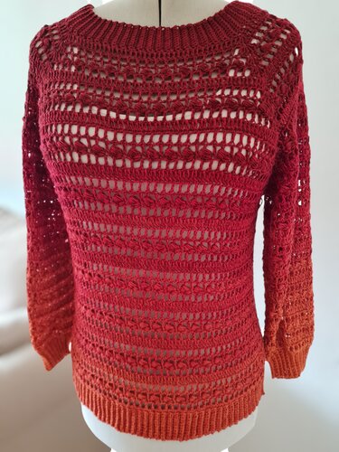 Rot‑Orange gehäkelter Damenpullover mit Ajourmuster auf Schneiderpuppe
