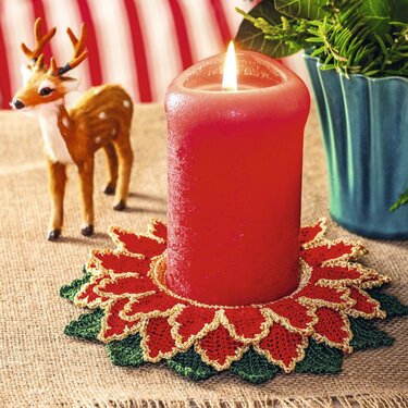 Gehäkelter roter Kerzenuntersetzer im Weihnachtsstern-Design mit goldfarbener Kante und grünen Blättern unter brennender roter Stumpenkerze
